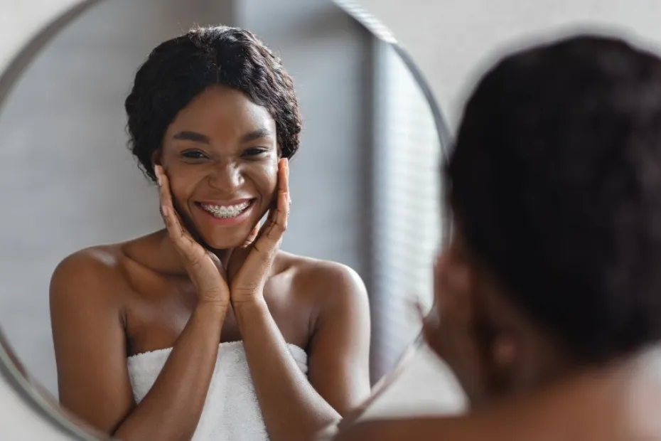 Mirror Reflection Of A Young Black Woman Applying Facial Product